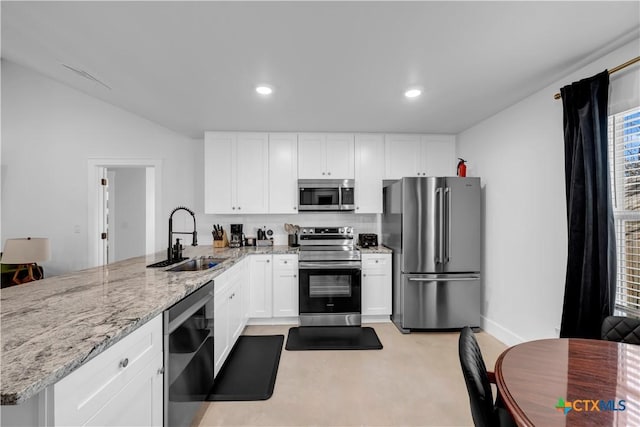 kitchen featuring white cabinetry, sink, light stone counters, kitchen peninsula, and stainless steel appliances