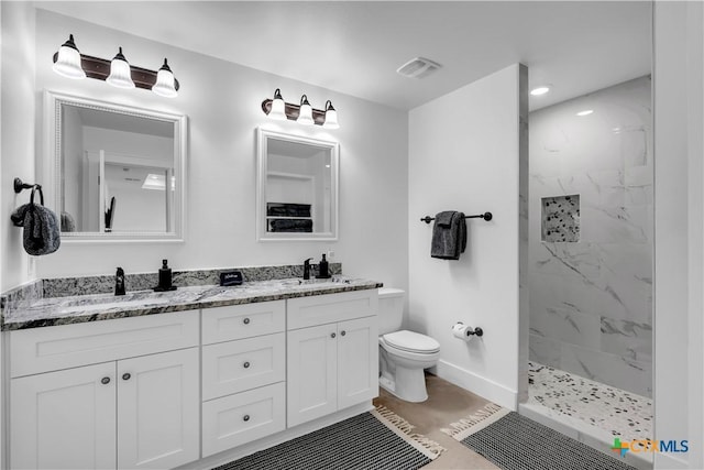 bathroom with vanity, toilet, tile patterned flooring, and a tile shower