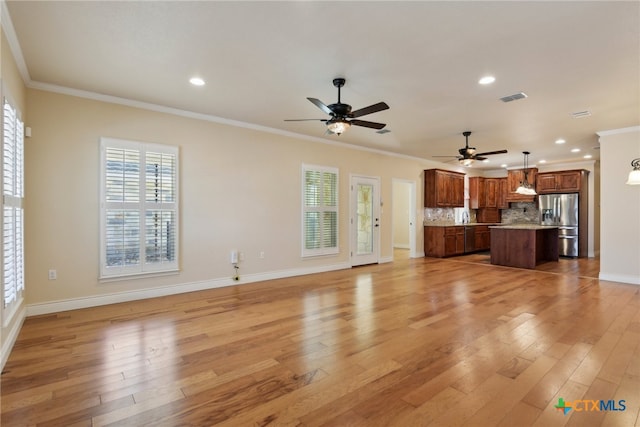 unfurnished living room featuring ceiling fan, sink, light wood-type flooring, and crown molding