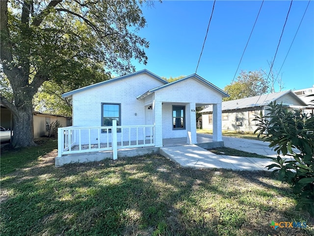 back of property featuring a lawn and covered porch