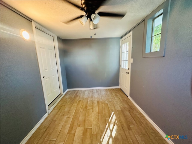 doorway to outside featuring ceiling fan, wood-type flooring, and a textured ceiling