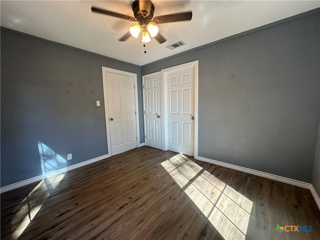 unfurnished bedroom featuring ornamental molding, ceiling fan, and dark wood-type flooring