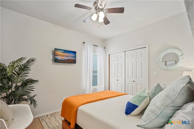 bedroom featuring a closet, baseboards, wood finished floors, and a ceiling fan