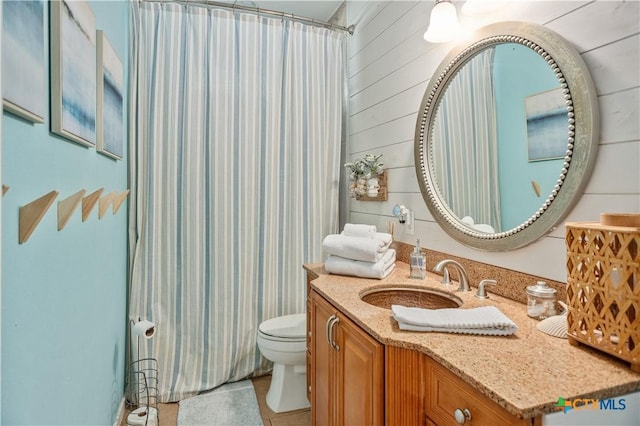 full bath featuring a shower with curtain, toilet, wood walls, tile patterned flooring, and vanity