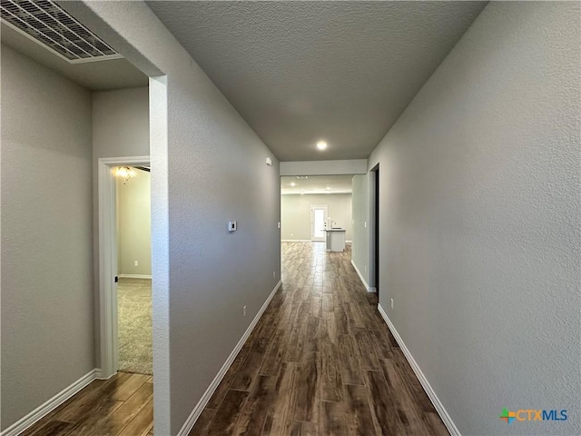 hallway with dark hardwood / wood-style floors and a textured ceiling