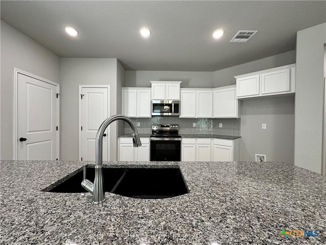 kitchen featuring white cabinetry, appliances with stainless steel finishes, sink, and dark stone countertops