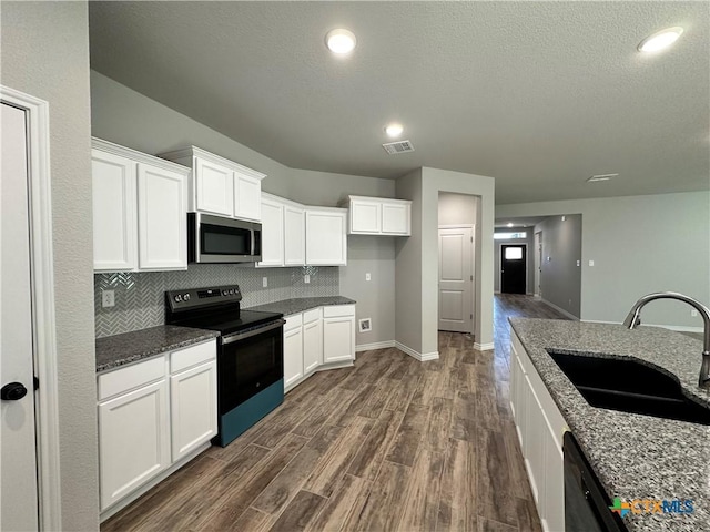 kitchen featuring dark wood-type flooring, sink, white cabinetry, black range with electric cooktop, and dark stone counters