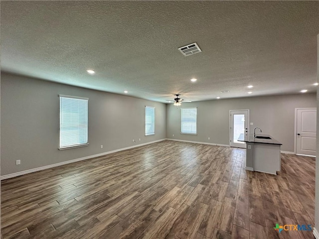 unfurnished living room with ceiling fan, dark hardwood / wood-style floors, sink, and a textured ceiling