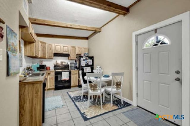 kitchen featuring black appliances, light tile patterned floors, sink, beamed ceiling, and light brown cabinetry