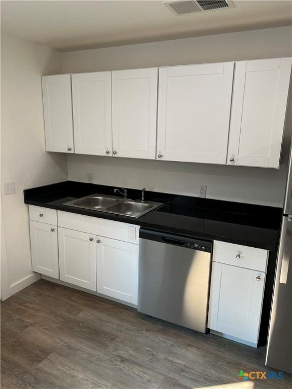 kitchen with white cabinets, dark hardwood / wood-style floors, stainless steel dishwasher, and sink