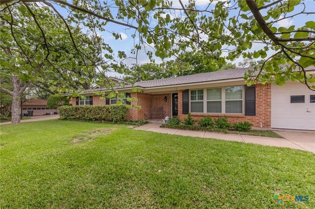 ranch-style house with brick siding, an attached garage, and a front lawn