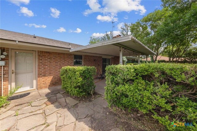 property entrance featuring brick siding and a patio