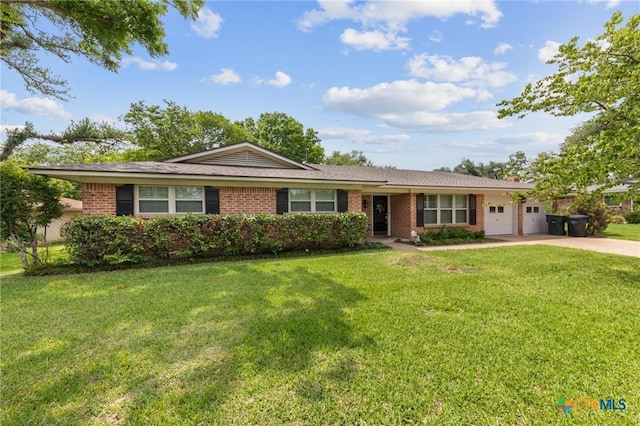 single story home featuring brick siding, a garage, a front lawn, and driveway