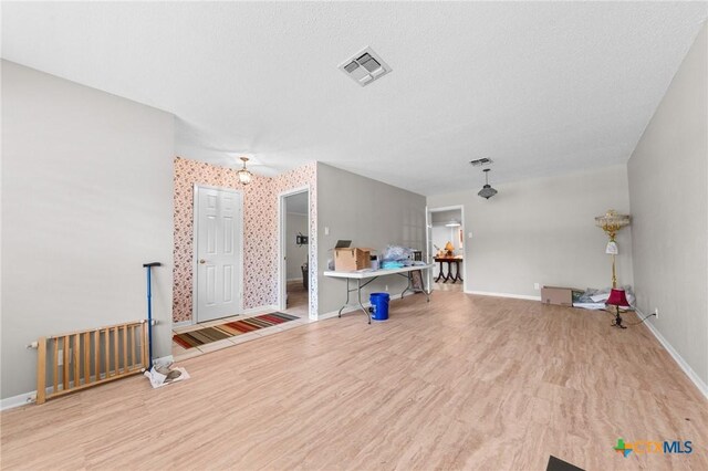 unfurnished living room with visible vents, baseboards, and wood finished floors