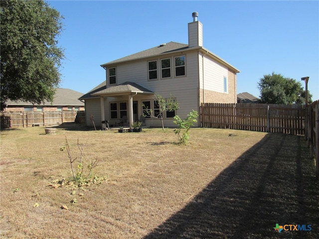 back of house with a patio area and a lawn