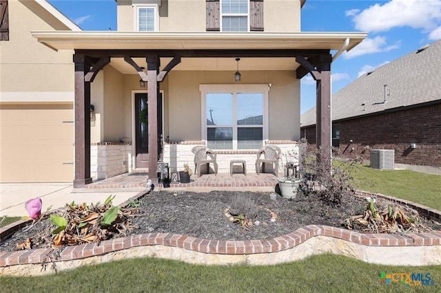 entrance to property featuring central AC, a porch, an attached garage, and stucco siding