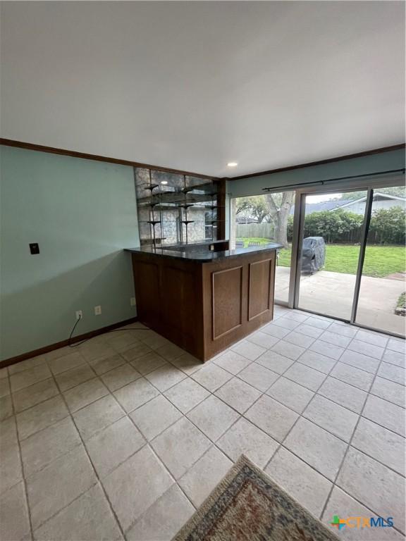 kitchen featuring dark countertops, light tile patterned flooring, a peninsula, and baseboards