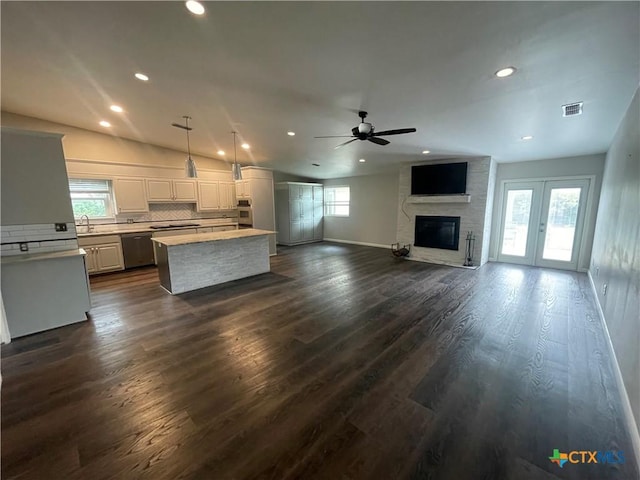 kitchen with a kitchen island, open floor plan, hanging light fixtures, stainless steel appliances, and light countertops