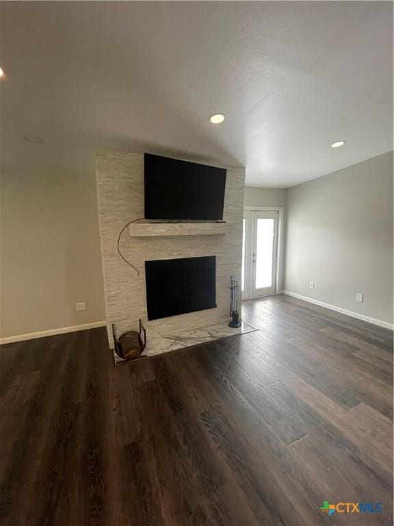 unfurnished living room featuring dark wood-style floors, recessed lighting, a large fireplace, and baseboards