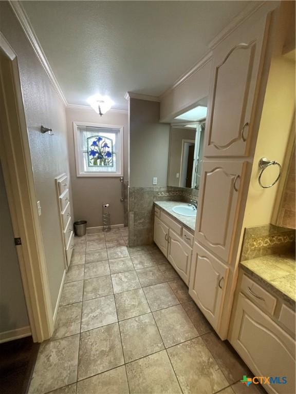 bathroom with tile patterned floors, crown molding, and vanity