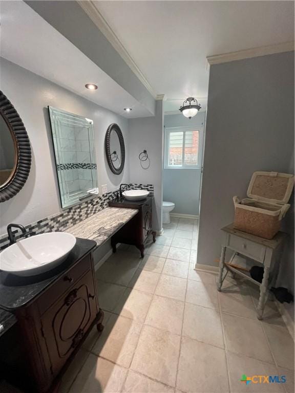 bathroom featuring toilet, tile patterned flooring, crown molding, and a sink