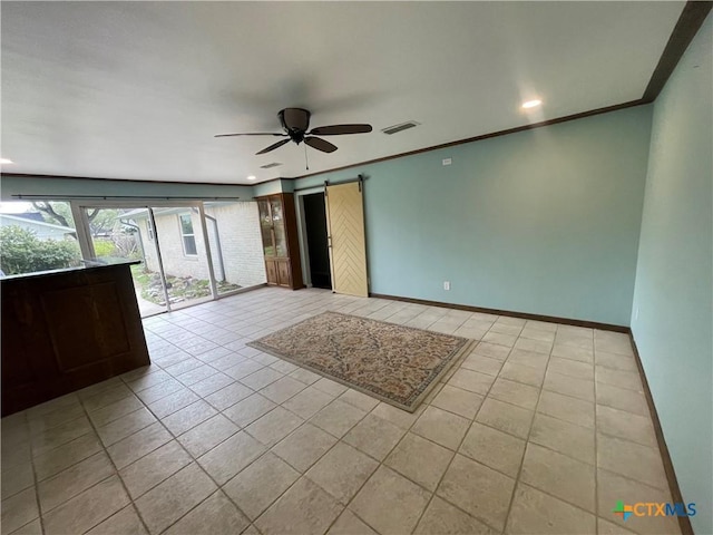 unfurnished room featuring light tile patterned floors, a barn door, baseboards, a ceiling fan, and ornamental molding