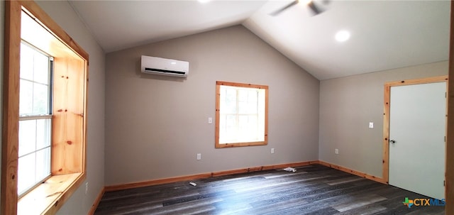 empty room with a wall mounted AC, dark hardwood / wood-style flooring, a healthy amount of sunlight, and vaulted ceiling