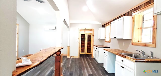 kitchen with a wall mounted AC, dark hardwood / wood-style flooring, sink, vaulted ceiling, and white cabinets