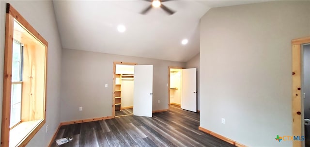 unfurnished bedroom with a walk in closet, a closet, lofted ceiling, and dark hardwood / wood-style flooring