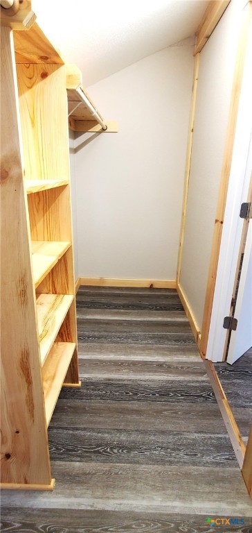 staircase with wood-type flooring and vaulted ceiling