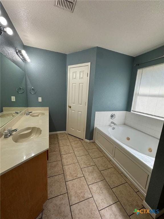 bathroom featuring tile patterned flooring, vanity, a washtub, and a textured ceiling