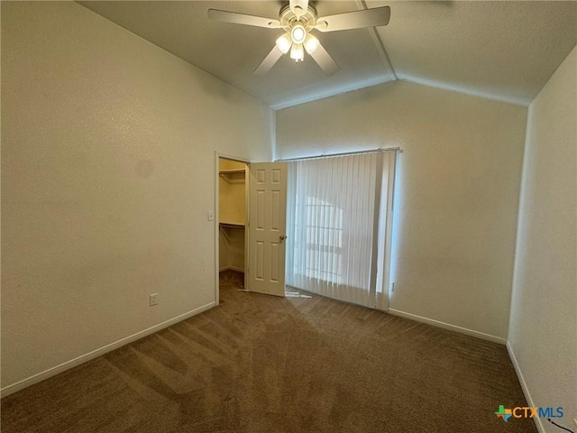 unfurnished bedroom featuring lofted ceiling, a spacious closet, ceiling fan, and carpet