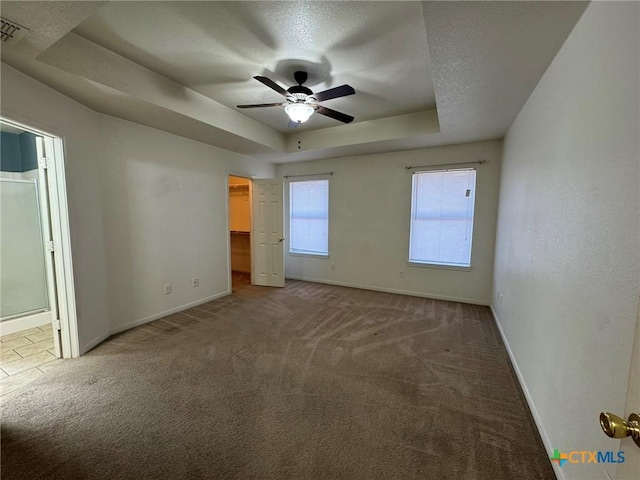 carpeted empty room with ceiling fan, a tray ceiling, and a textured ceiling