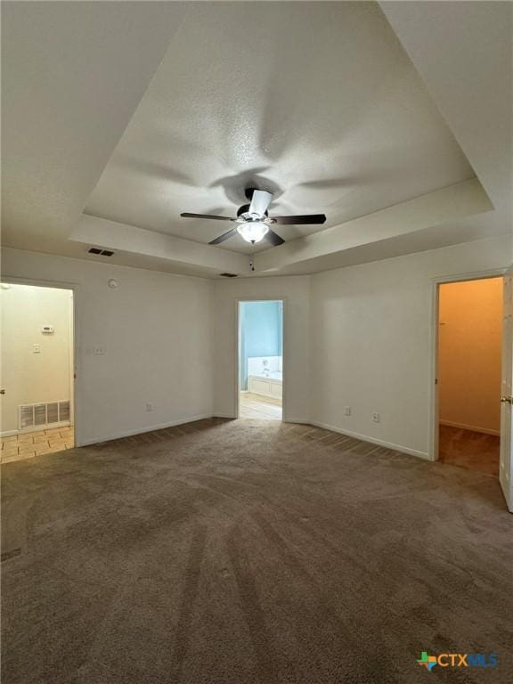 carpeted empty room featuring ceiling fan and a tray ceiling