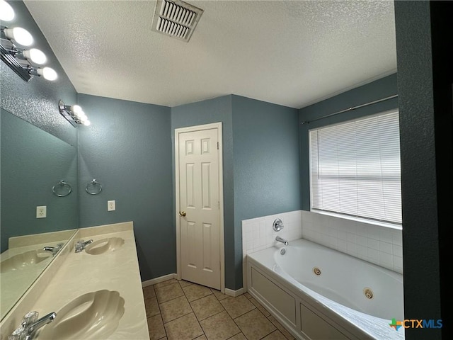 bathroom with tile patterned floors, vanity, a textured ceiling, and a tub