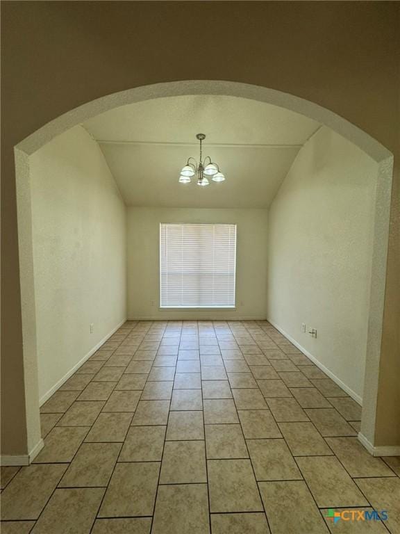 spare room featuring vaulted ceiling, light tile patterned floors, and a chandelier