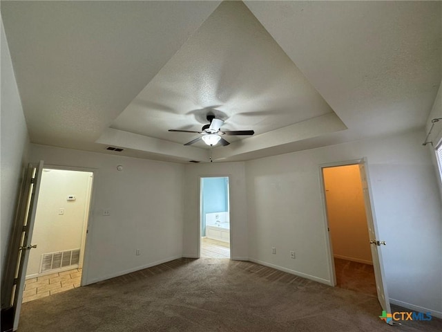 unfurnished room featuring a raised ceiling, a textured ceiling, and dark colored carpet