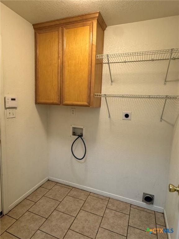 laundry area featuring electric dryer hookup, hookup for a washing machine, cabinets, and a textured ceiling