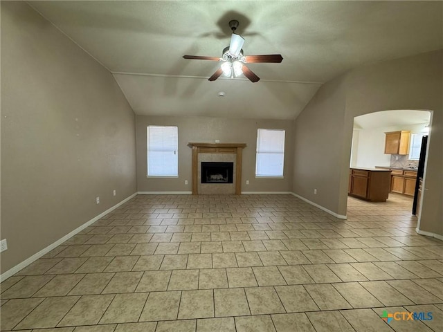 unfurnished living room with ceiling fan, lofted ceiling, a healthy amount of sunlight, and a fireplace