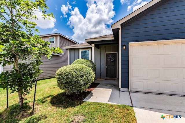 property entrance featuring a garage and a yard