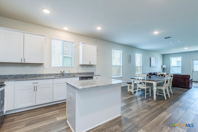 kitchen featuring white cabinetry, sink, light stone countertops, dark hardwood / wood-style floors, and a center island