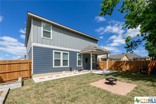 back of property featuring a patio, a yard, and a fire pit