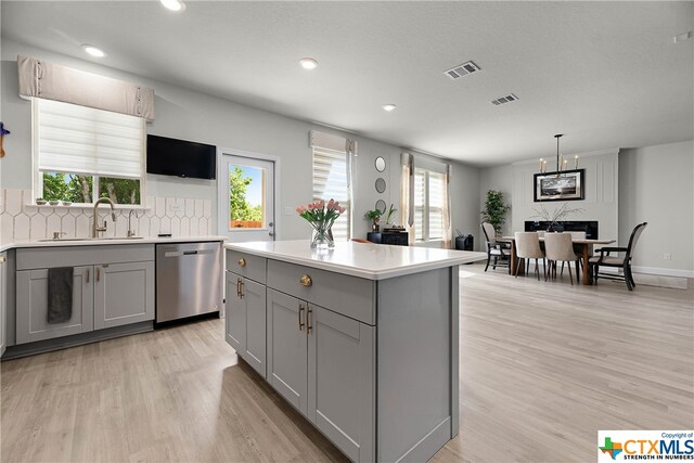 kitchen featuring gray cabinets, a healthy amount of sunlight, and dishwasher