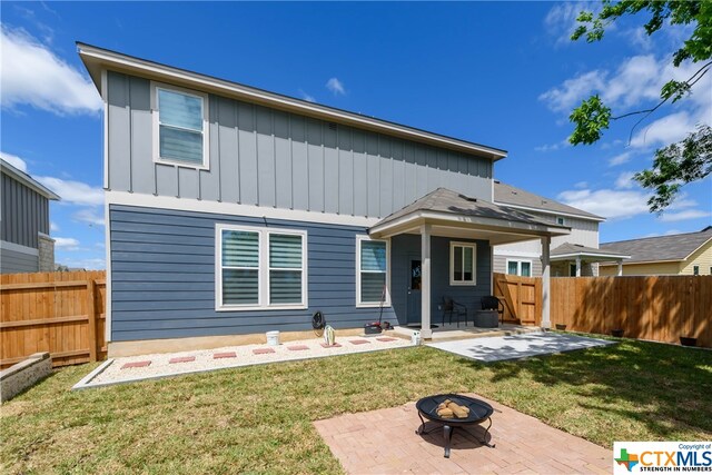 rear view of house with a patio, a lawn, and a fire pit