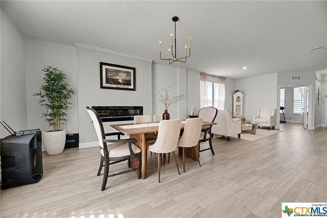 dining space with light hardwood / wood-style floors and an inviting chandelier