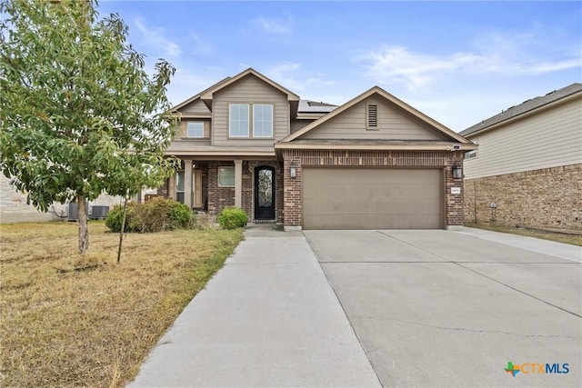 craftsman-style home featuring a garage, driveway, solar panels, a front lawn, and brick siding