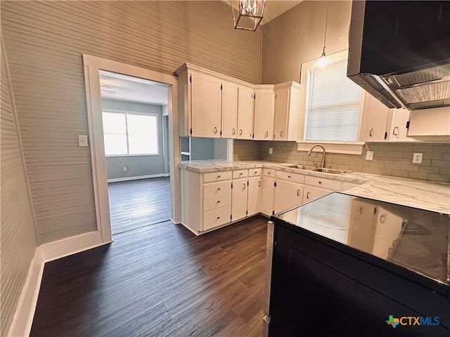 207 Schrimsher St, Yoakum, TX 77995 - kitchen featuring extractor fan, dark wood-style floors, white cabinetry, decorative backsplash, and a high ceiling