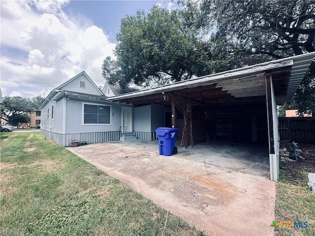 207 Schrimsher St, Yoakum, TX 77995 - view of front of home featuring concrete driveway, a front yard, and an attached carport