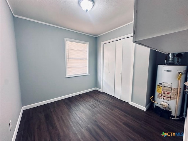 207 Schrimsher St, Yoakum, TX 77995 - unfurnished bedroom with water heater, ornamental molding, dark wood finished floors, and a closet