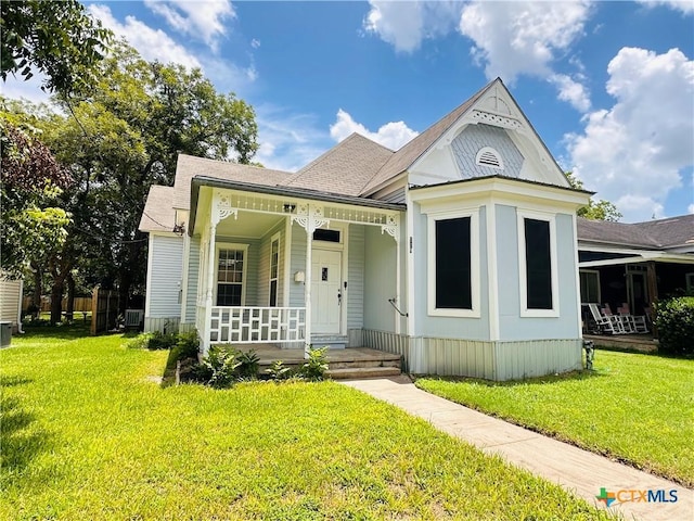 207 Schrimsher St, Yoakum, TX 77995 - victorian home with a porch, a front yard, and a shingled roof